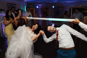 Wedding party members dance and pose playfully in a reception venue with purple lighting and festive atmosphere.