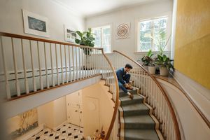 A curved staircase with white wooden railings and yellow walls leads upstairs in an elegant residential interior.