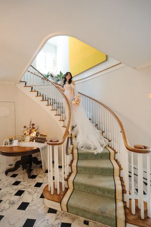 A sequence of photos showing a wedding dress flowing down an elegant curved staircase with white railings.