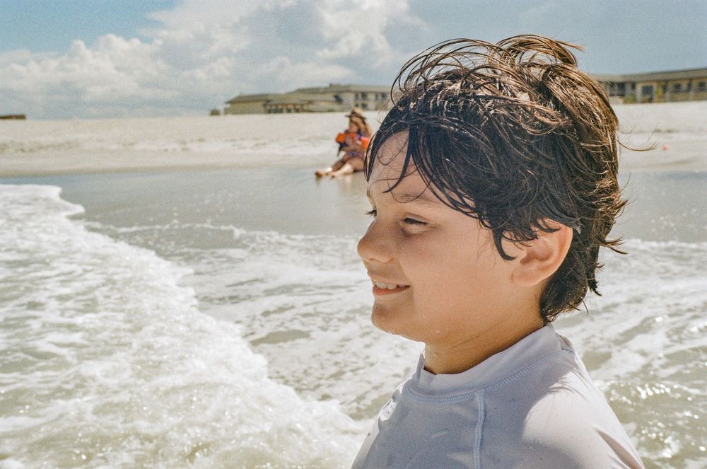 A joyful moment at the beach with waves crashing and sand in the background.