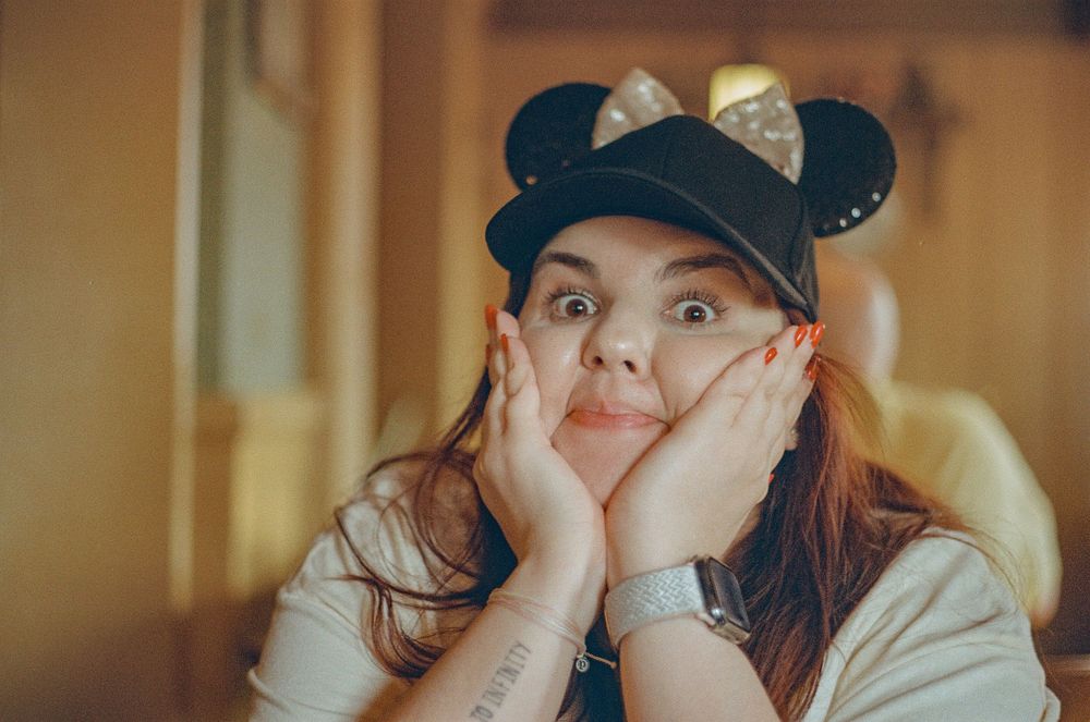 A playful pose wearing a Minnie Mouse ears hat indoors.