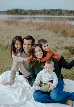 Family portrait on white blanket in autumn field near lake.