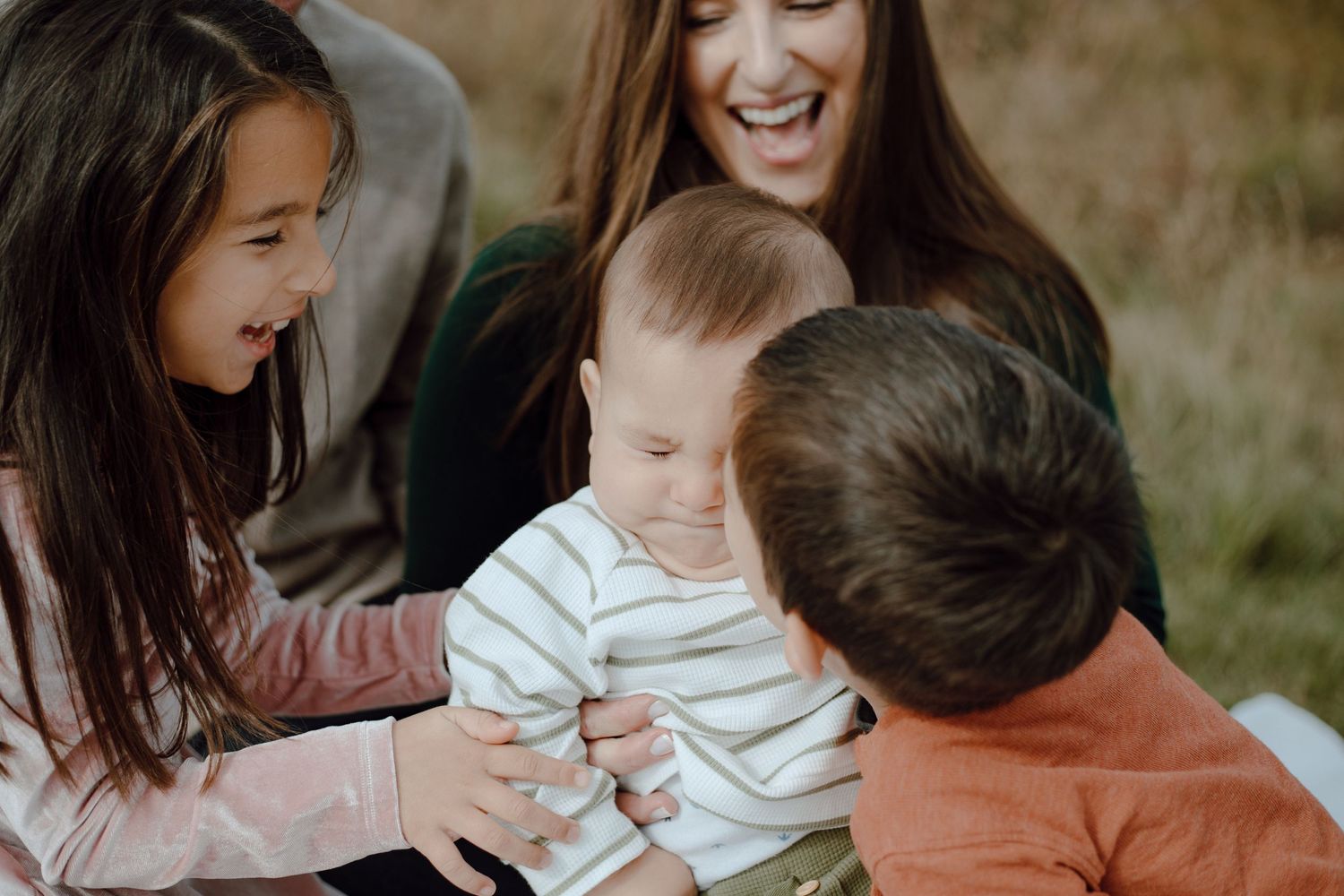 Candid family moment sharing laughter while sitting together outdoors.
