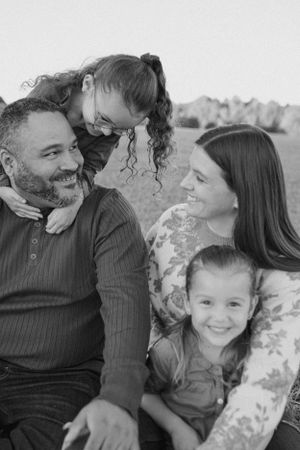 A black and white family portrait captures a candid moment of joy and connection.