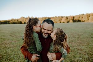 An intimate family moment captured during golden hour in an autumn field.