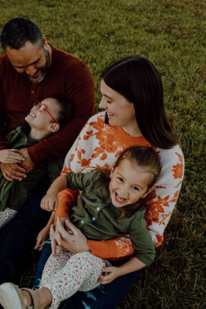 A candid family portrait shows genuine laughter and joy during an outdoor photo session.