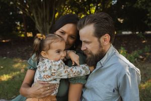 An intimate family portrait captured outdoors with soft natural lighting.