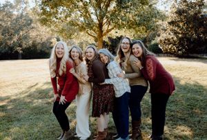 Group of friends posing together and laughing in an outdoor autumn setting.