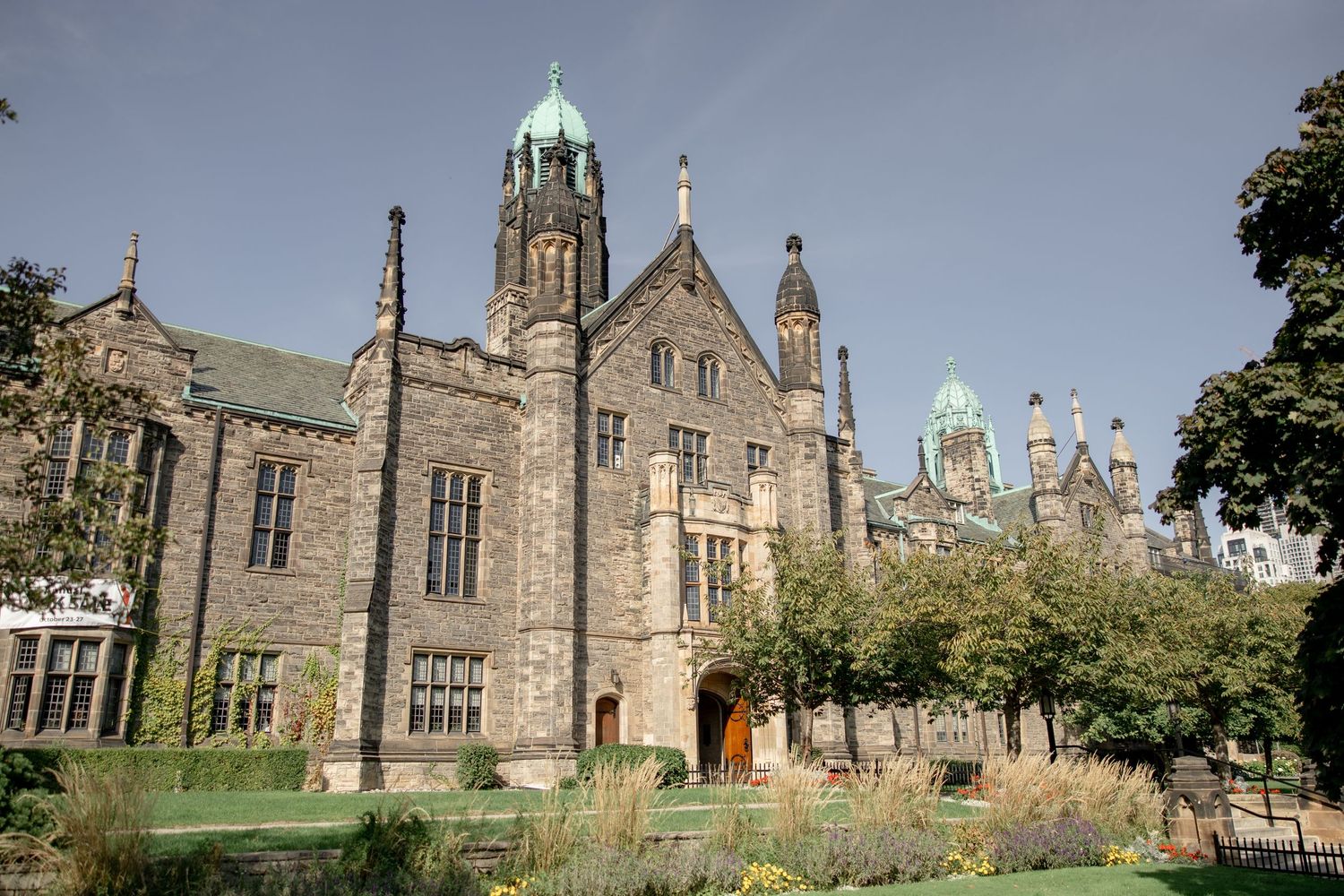 Gothic revival architecture of a stone university building with ornate windows and copper spires.