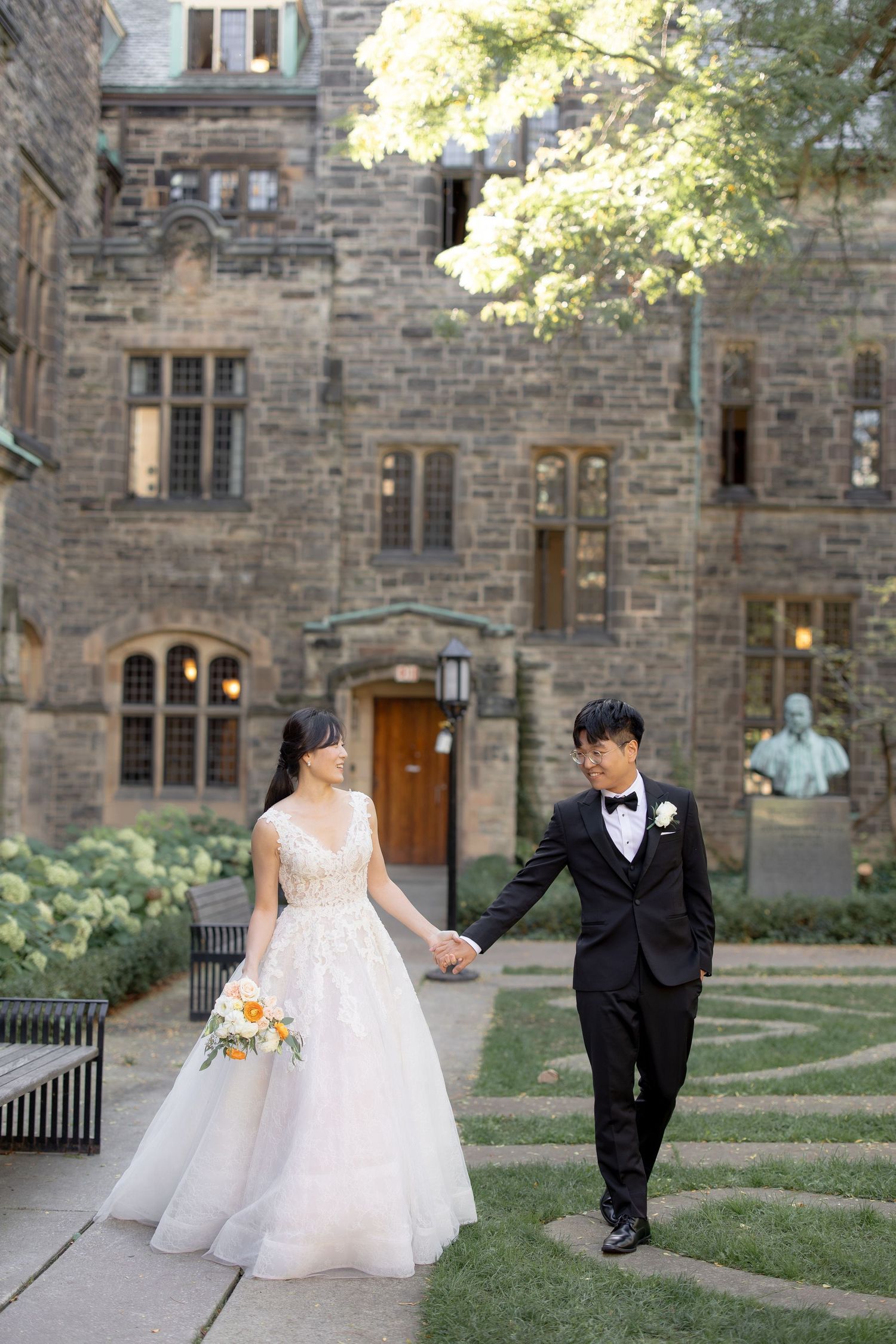A romantic wedding portrait on manicured grounds of a gothic stone building.