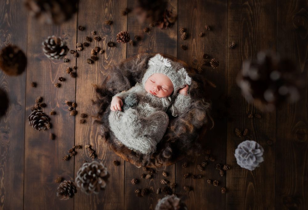 Rustic flat lay of pinecones and soft textured items on dark wooden surface.