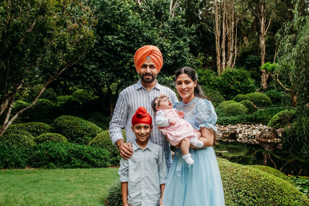 Family portrait session in a lush garden setting with warm evening sunlight.