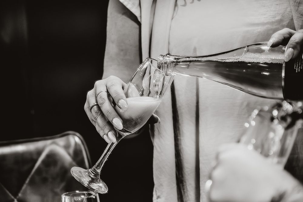 Black and white detail shots of champagne being poured at an elegant event.