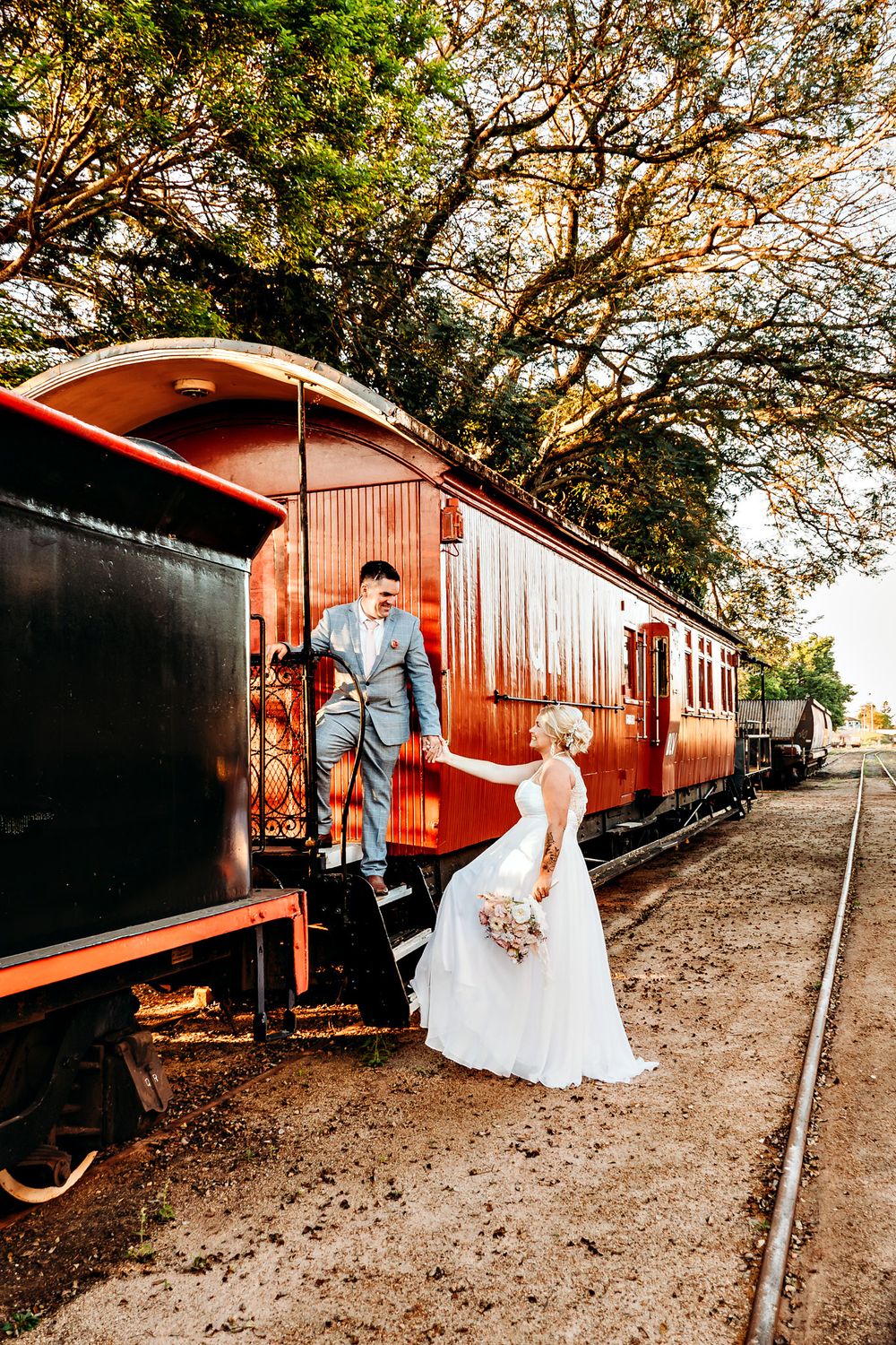 Vintage train station wedding photography with rustic red carriages and autumn trees.