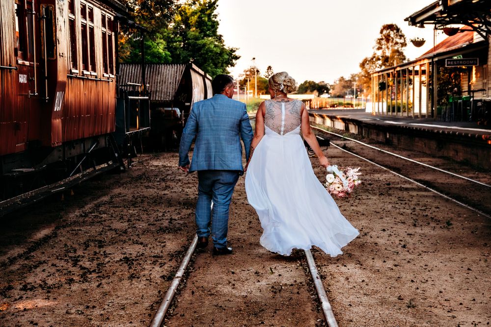 Romantic sunset wedding photos along vintage train tracks with rustic carriages.