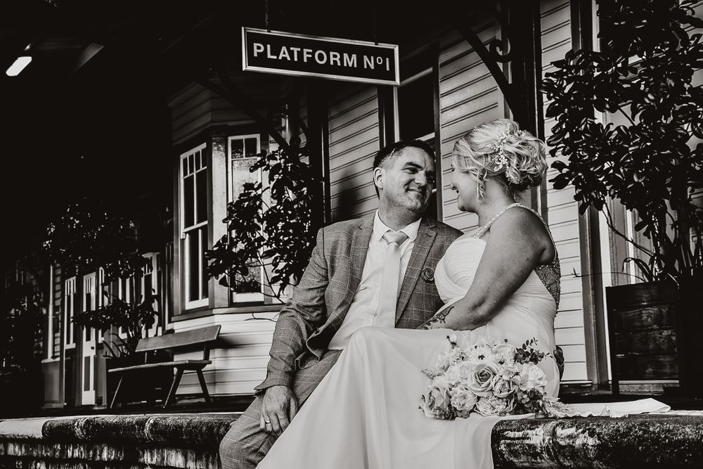 A wedding ceremony taking place at a rustic train station platform with vintage decor and wooden details.