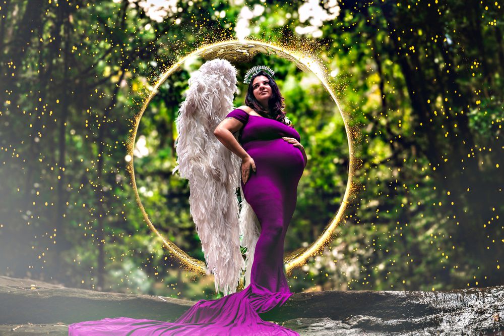 Maternity photo with woman in purple dress against glowing circular backdrop in forest.