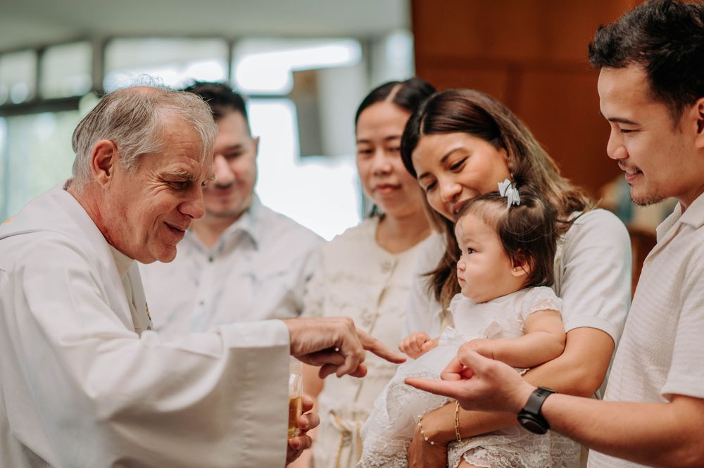 Religious ceremony with family and clergy member in white clothing.
