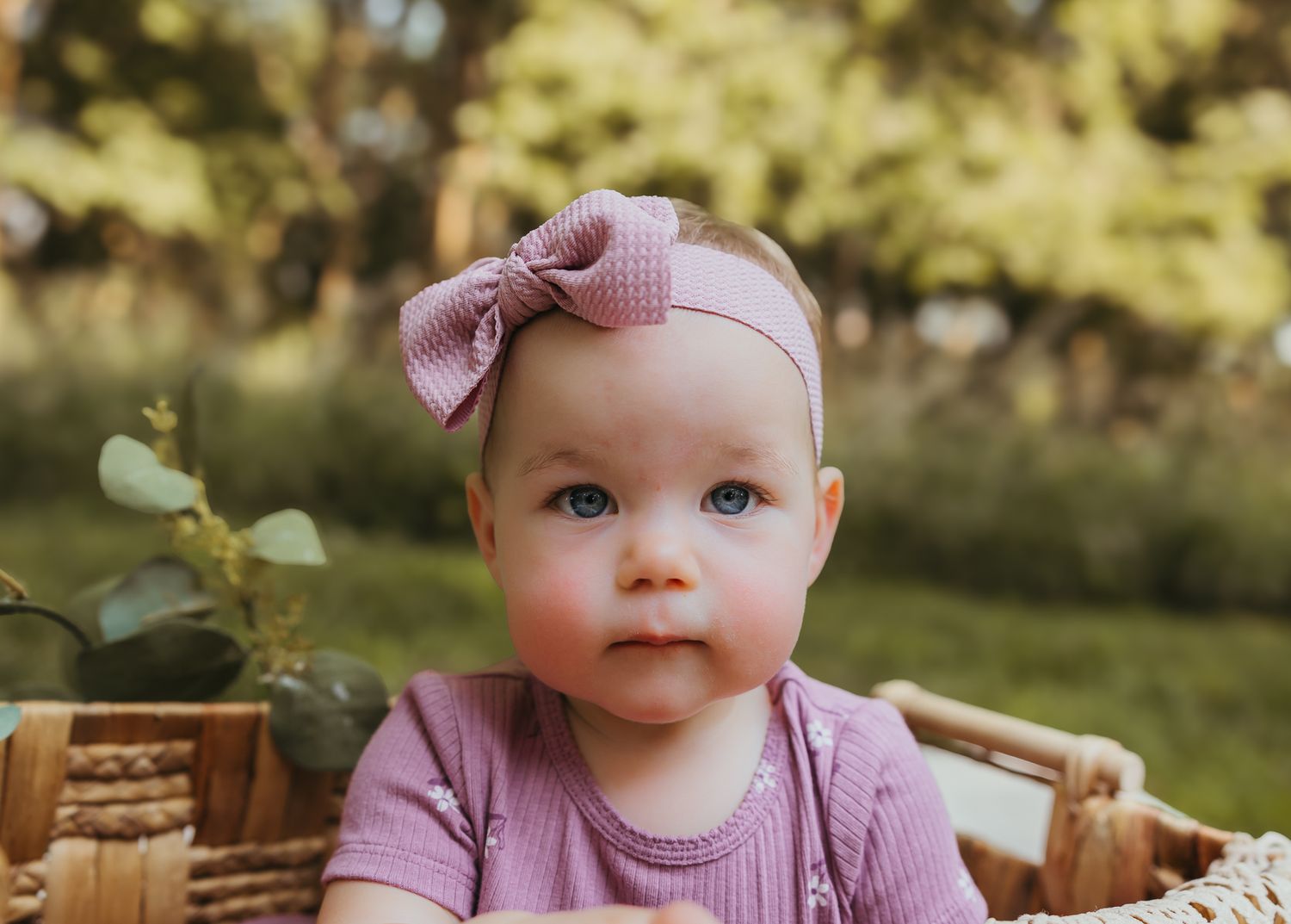 Close up shot of a pink bow headband and matching outfit in a rustic basket setting. Colorado Springs Photographer.
