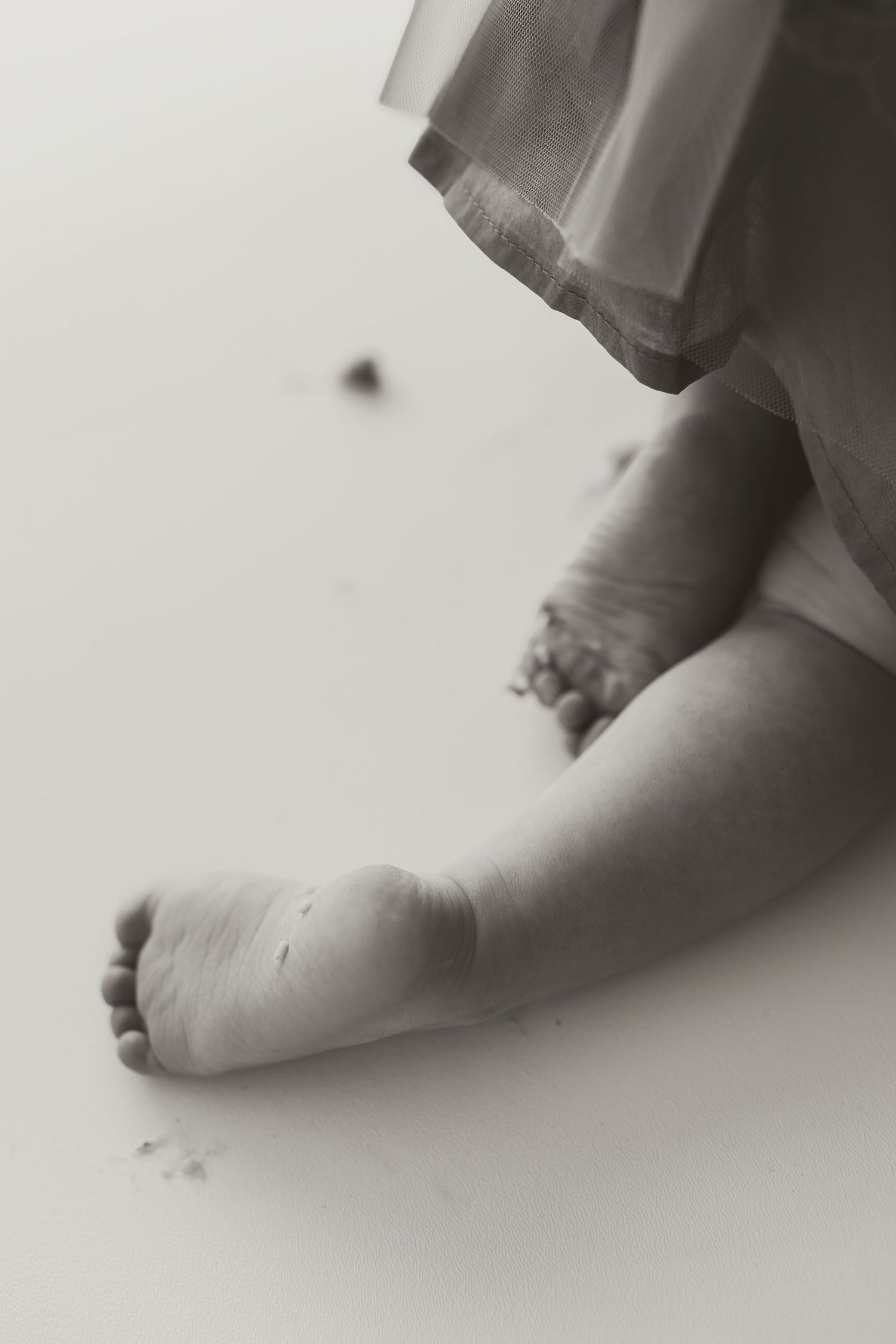 A black and white close-up photograph of tiny baby feet against a light background. Colorado Springs Photographer.
