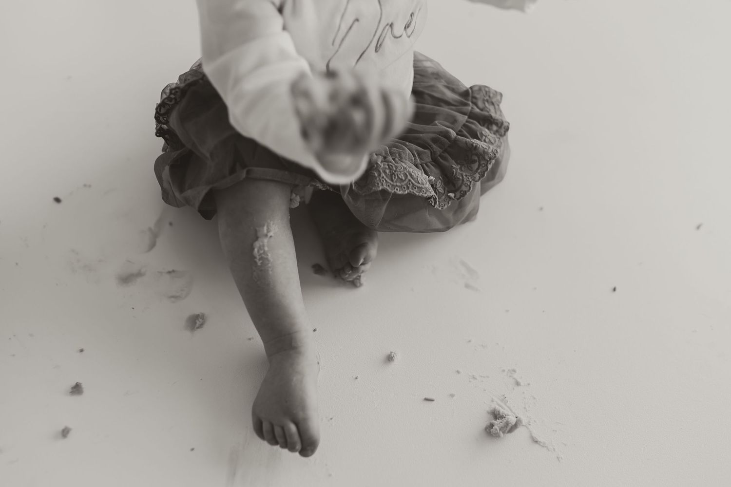 Black and white image of a small bare foot with a ruffled skirt hem visible above. Colorado Springs Photographer.