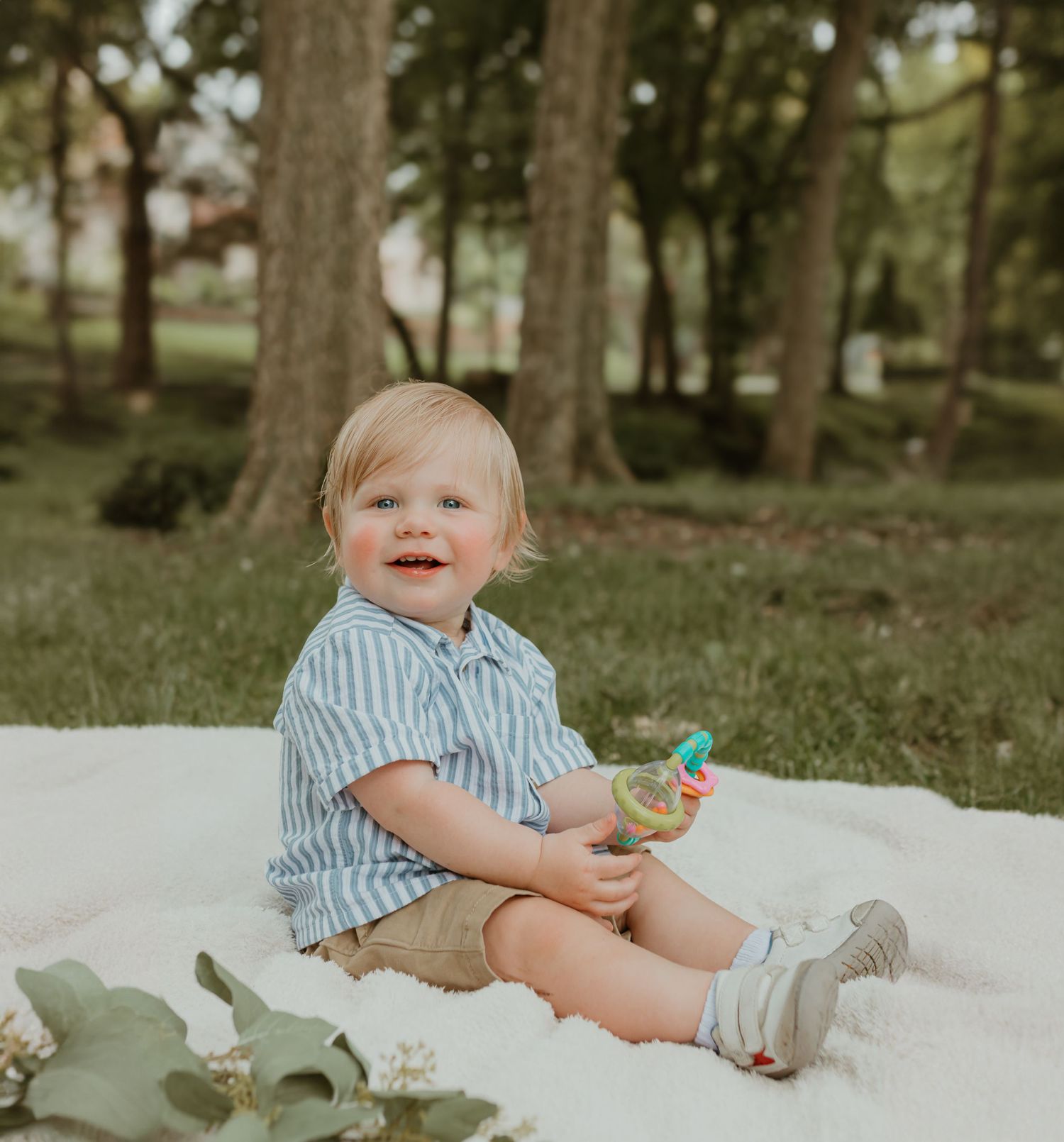 A happy outdoor photo session on a white blanket with a small toy. Colorado Springs Photographer.