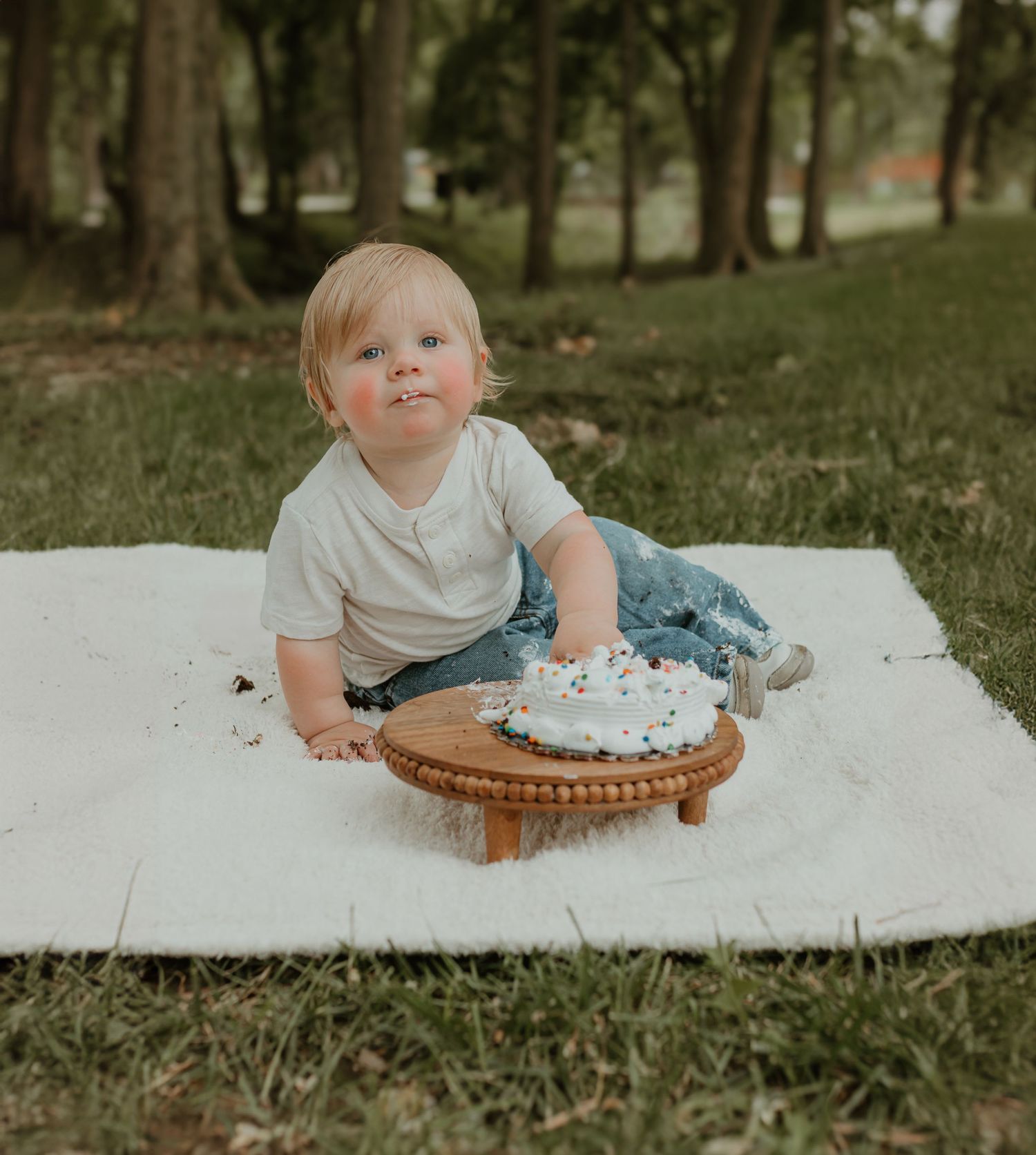 A small cake smash photo session outdoors with a decorated cake on a wooden stand. Colorado Springs Photographer