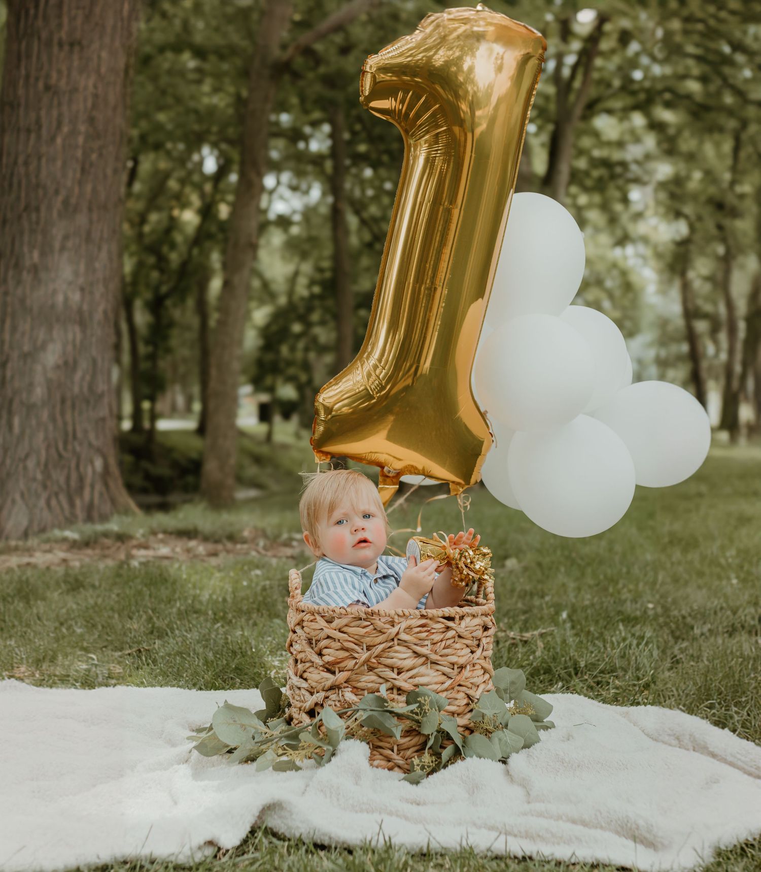 First birthday celebration setup with gold balloon and white decorations in an outdoor setting. Colorado Springs Photographer
