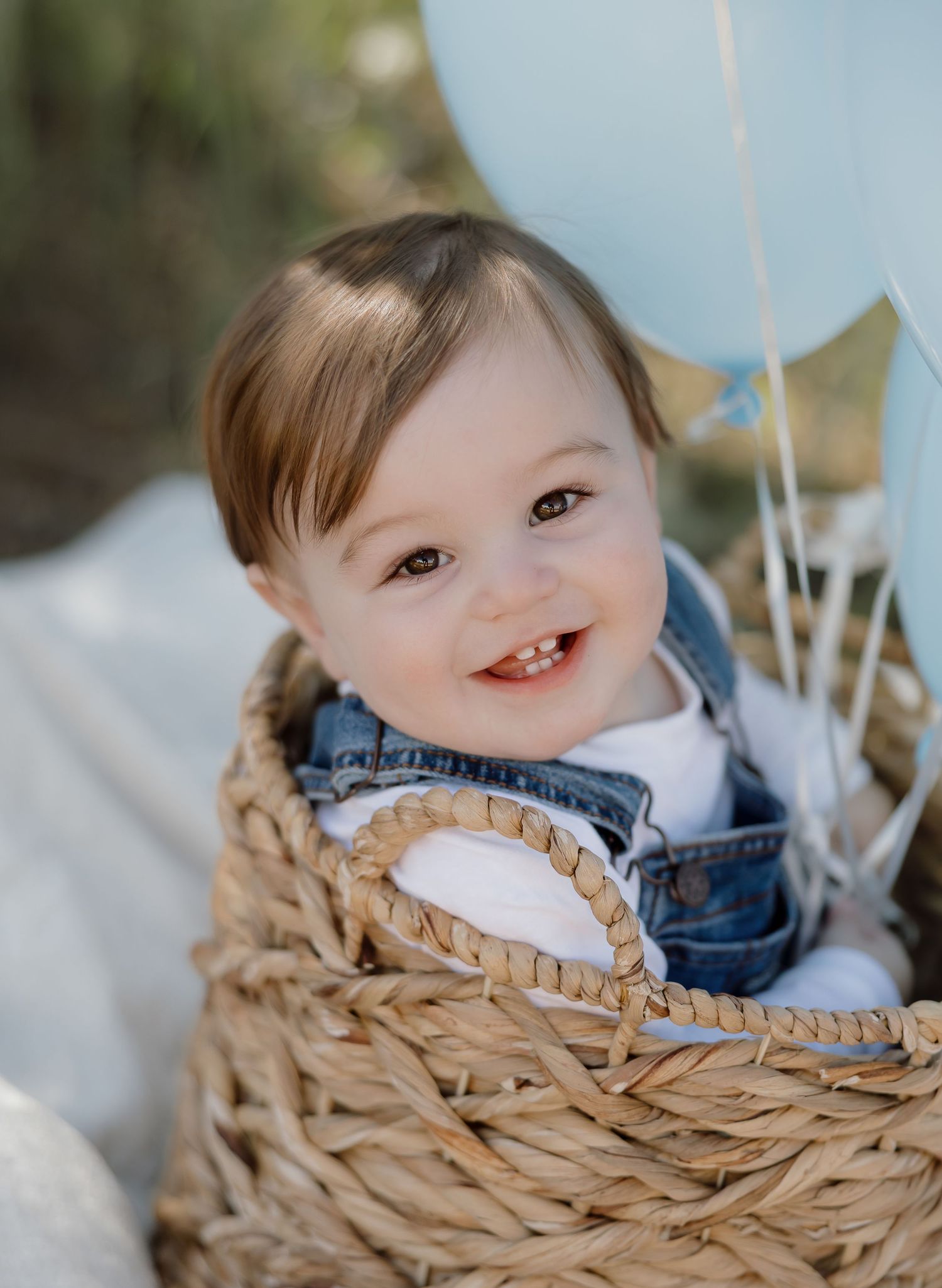 A smiling child peeks over the edge of a woven wicker basket in a series of candid photos.