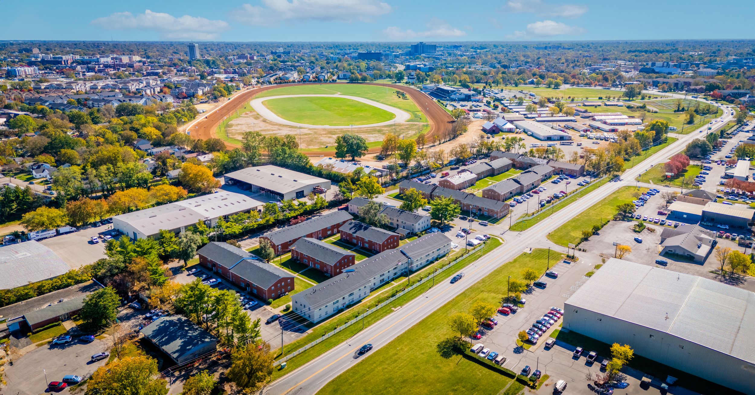 Aerial view of a sports stadium complex surrounded by residential buildings and parking lots.