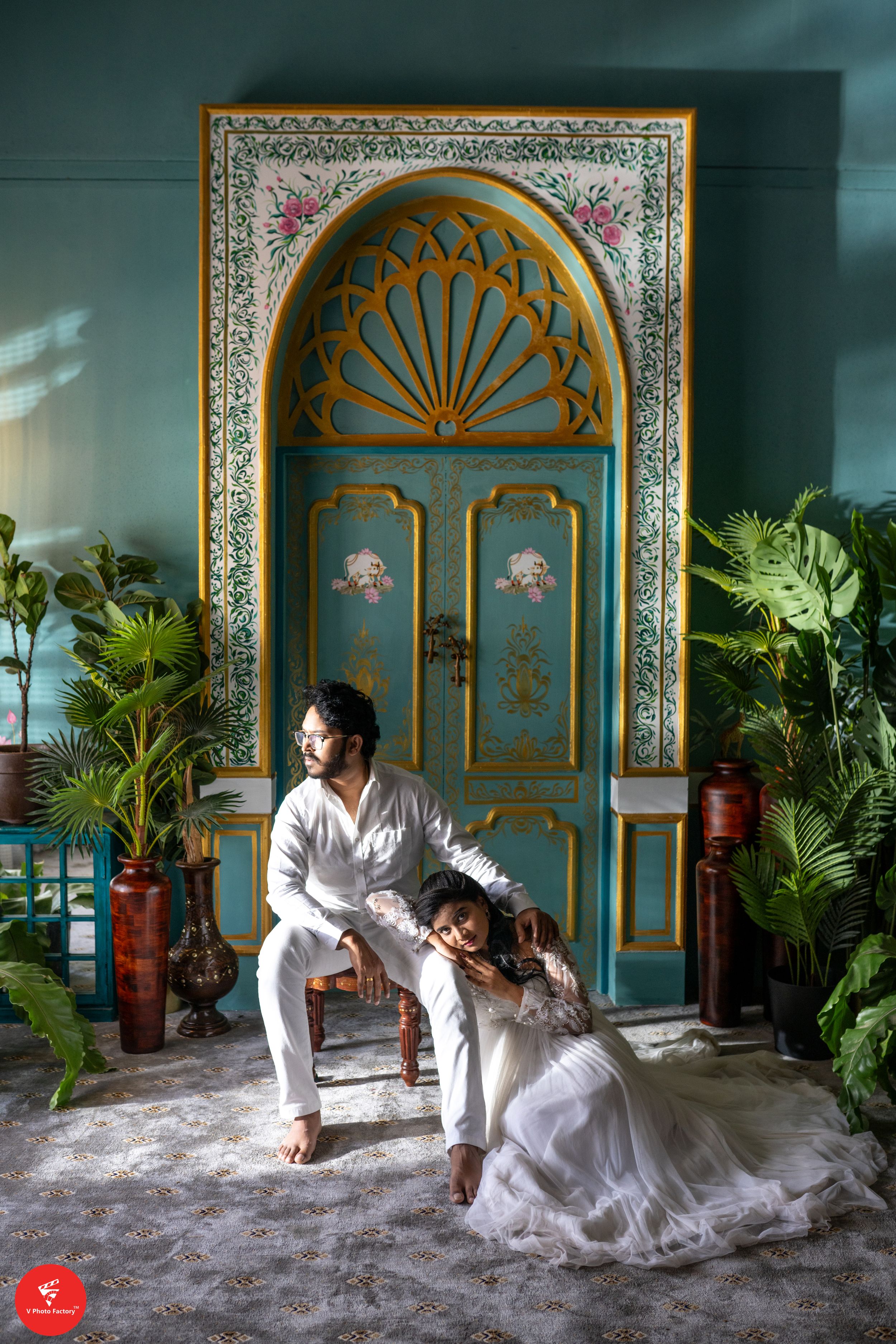 An ornate turquoise door serves as backdrop for an artistic pose against tropical plants.