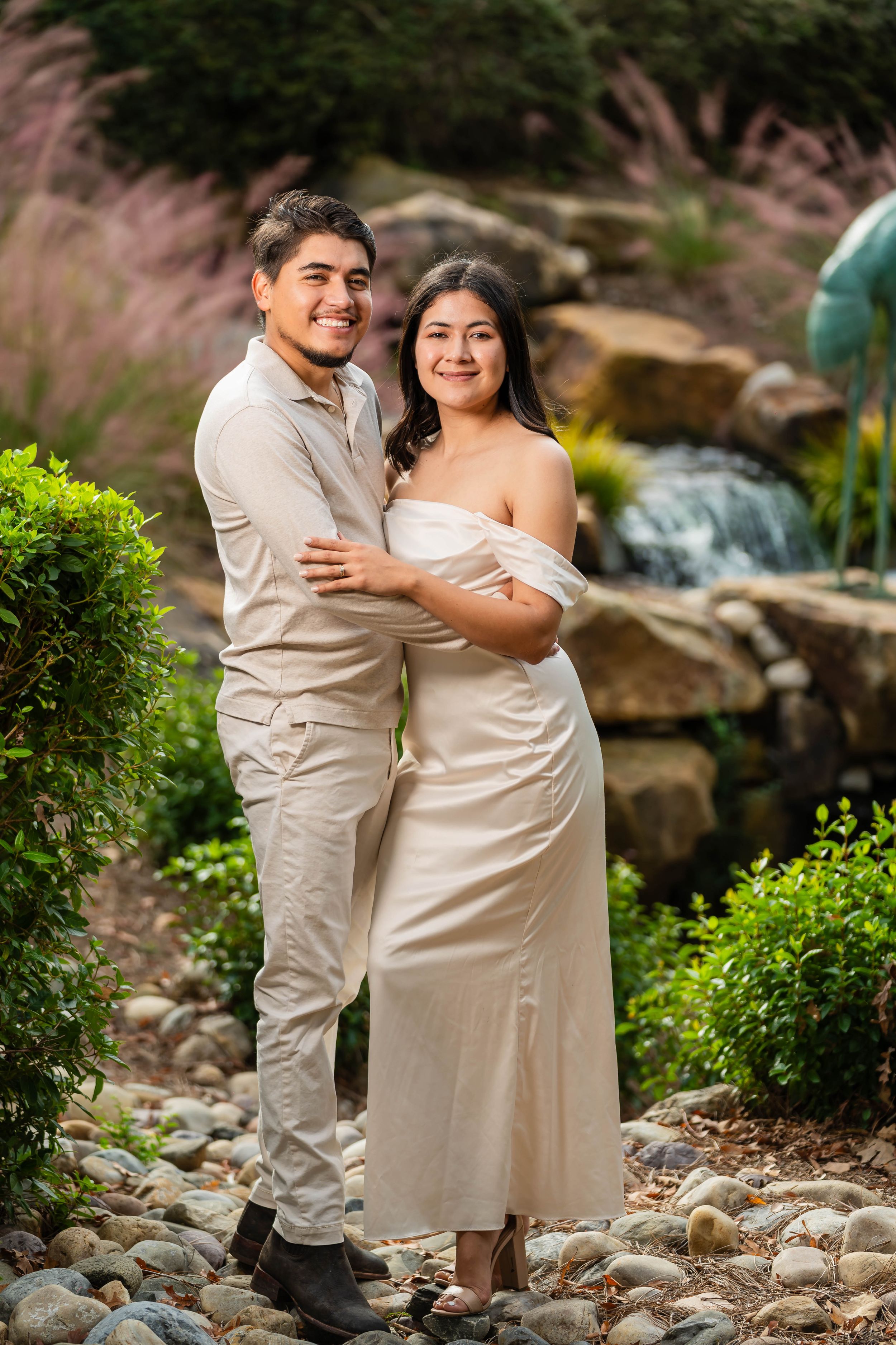 A romantic engagement photo by a landscaped waterfall garden.