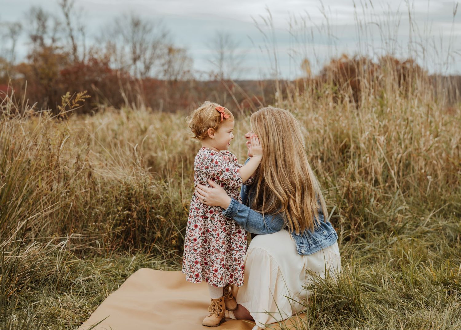 A sweet moment between parent and child sitting together in a field of tall grass.