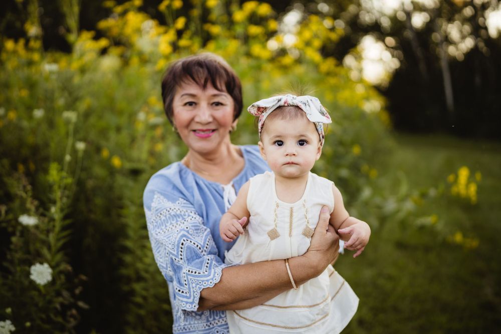 A tender moment captured between a caregiver and baby in a summery outdoor setting.