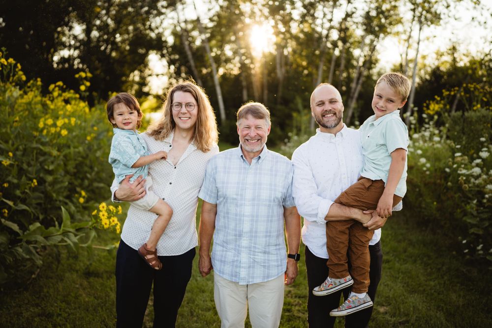 Group poses in coordinated white and blue outfits during outdoor family photo session.