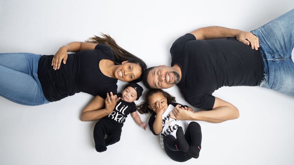 Couple lying on white background in casual denim outfits during photo session.