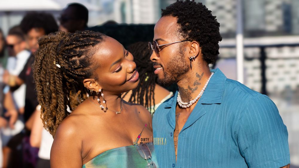 Couple shares intimate moment against scenic waterfront backdrop.