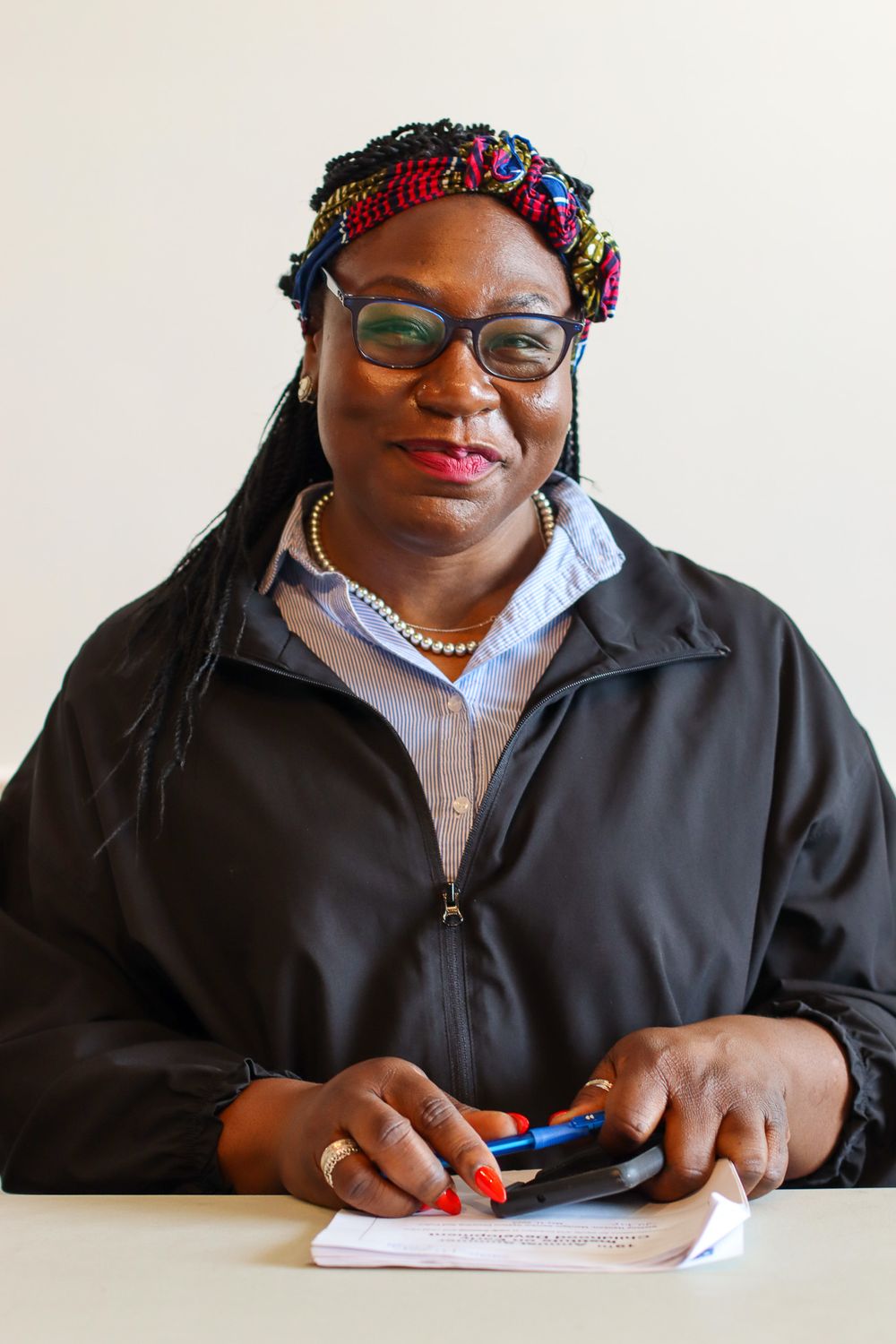 Professional wearing a colorful headband and black jacket writing on a notepad.