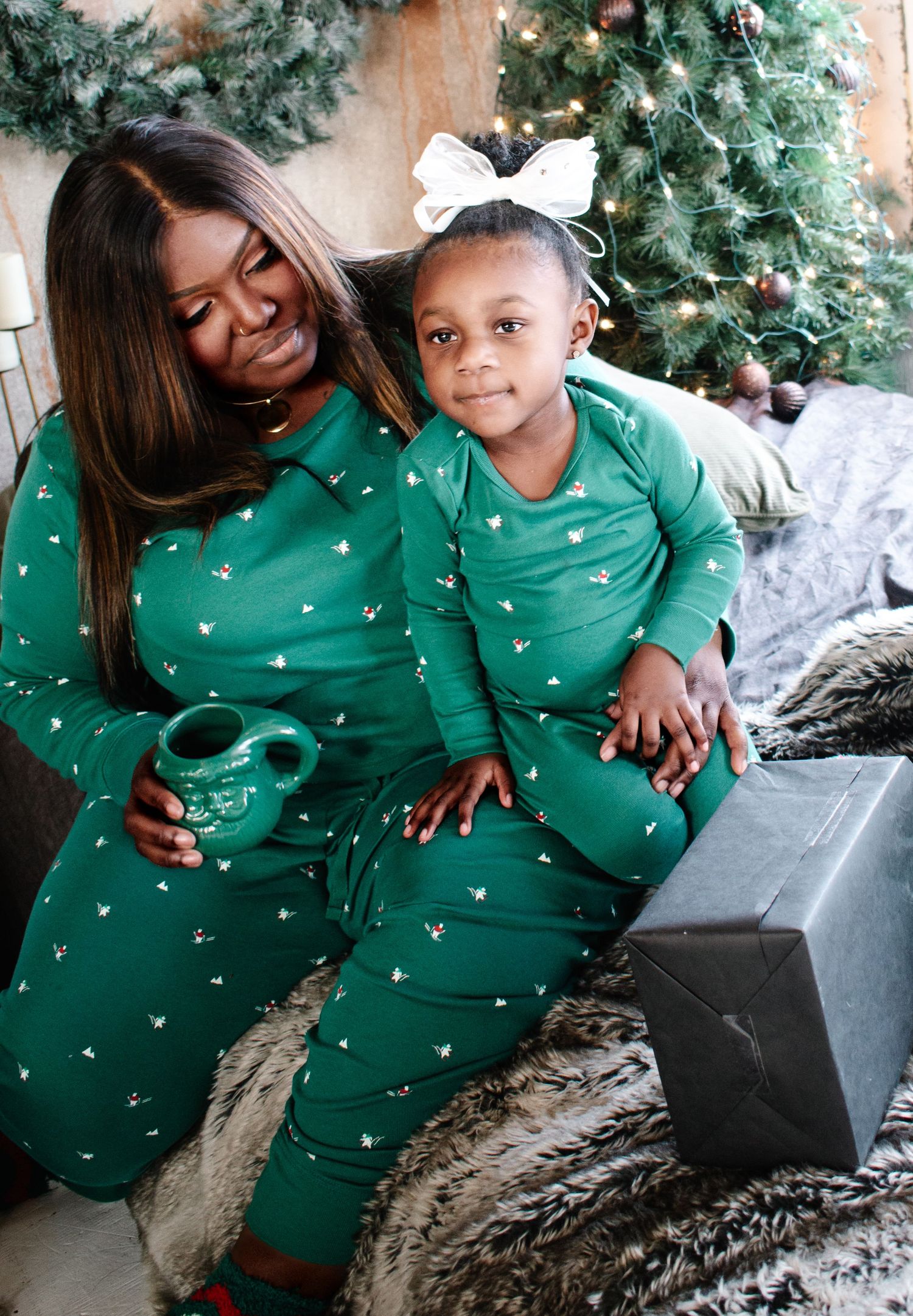 Family, mother and daughter, sitting on bed in matching green pajamas during Christmas photo session in Tacoma studio