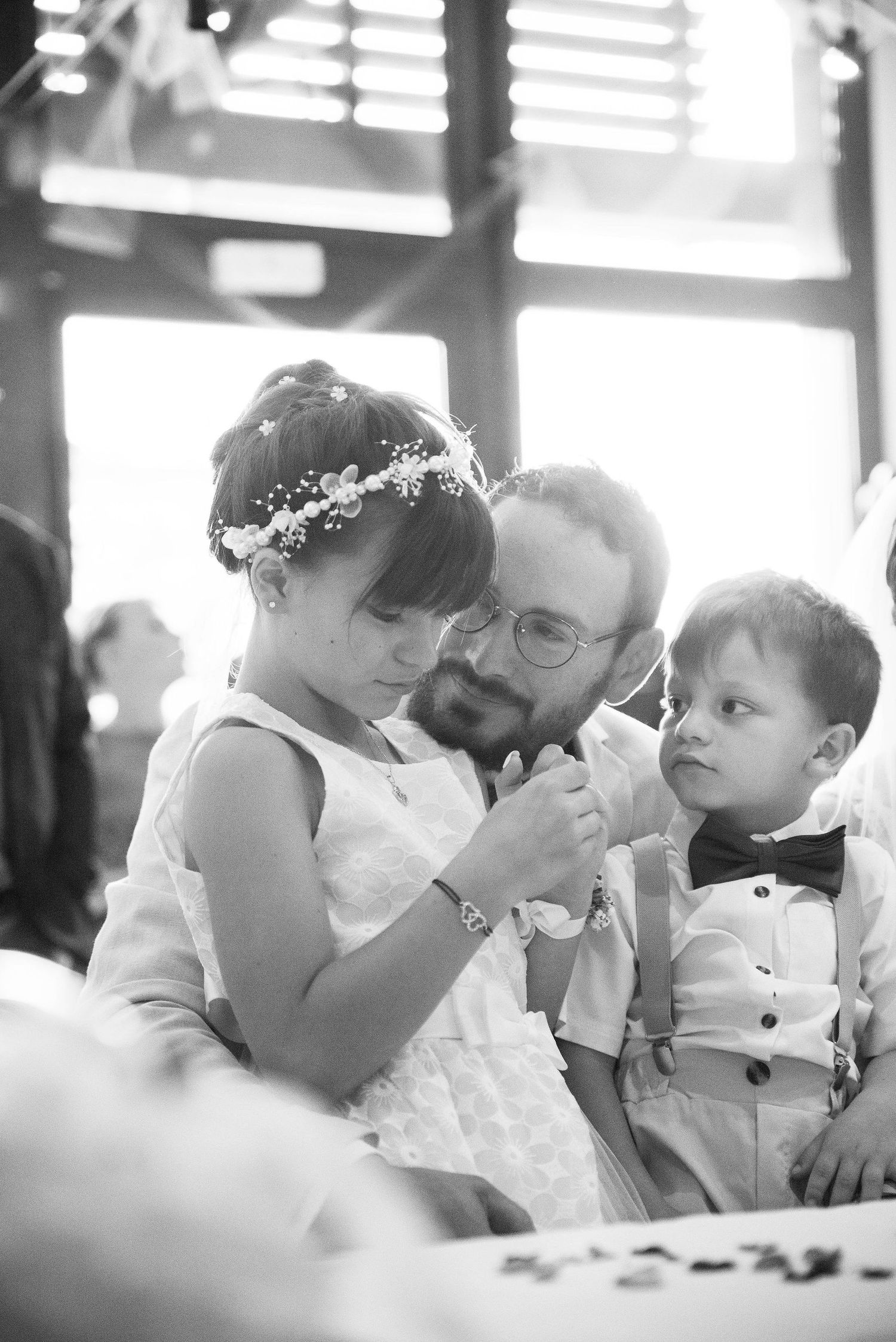Un moment de douceur capturé entre un père et ses deux enfants, dans une lumière tamisée qui souligne l’émotion partagée lors d’un événement