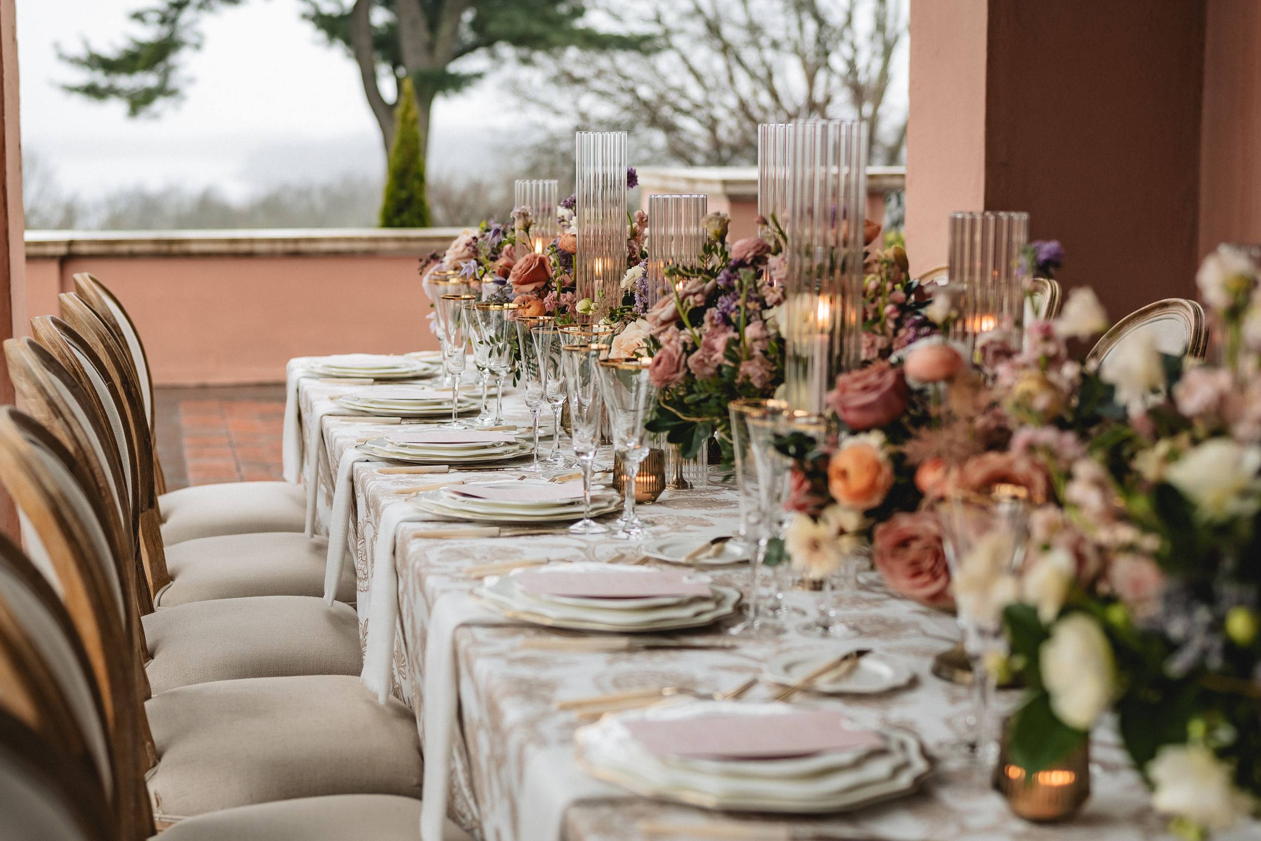 Elegant wedding table setting with floral centerpieces, place settings, and plush chairs in muted tones.