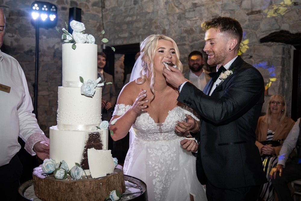 Wedding reception dance floor moments with elegant white cake and stone wall backdrop.