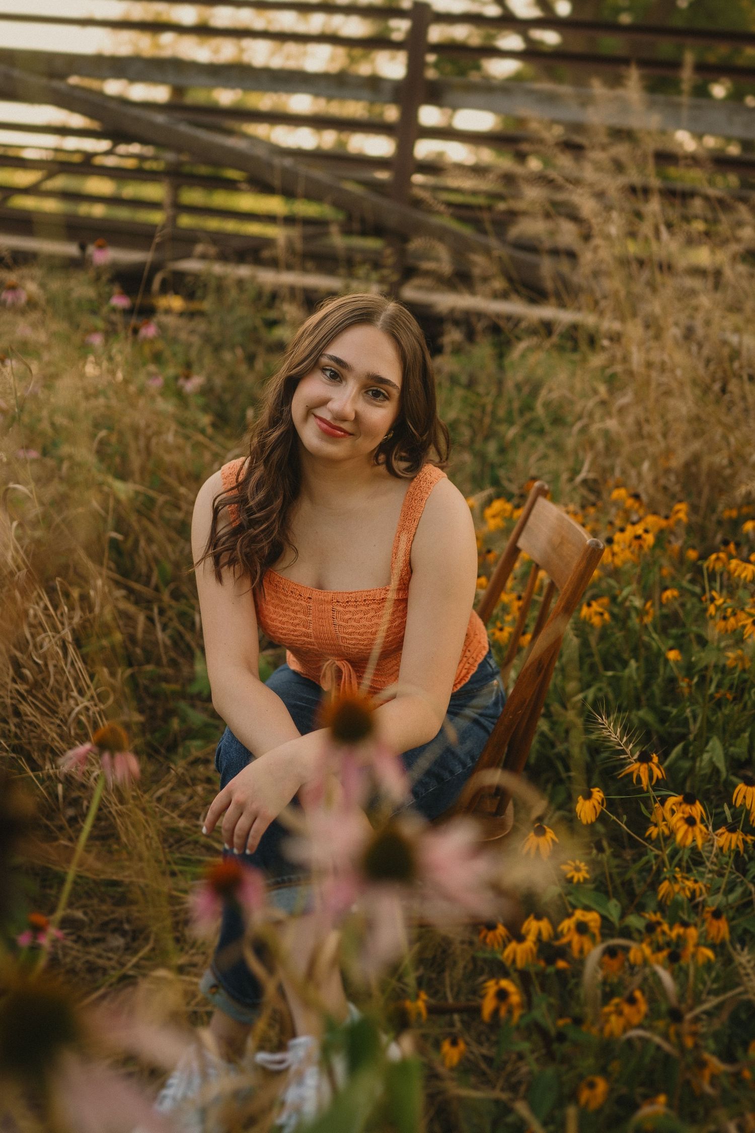 Natural outdoor portrait among vibrant orange wildflowers and tall grasses at sunset.