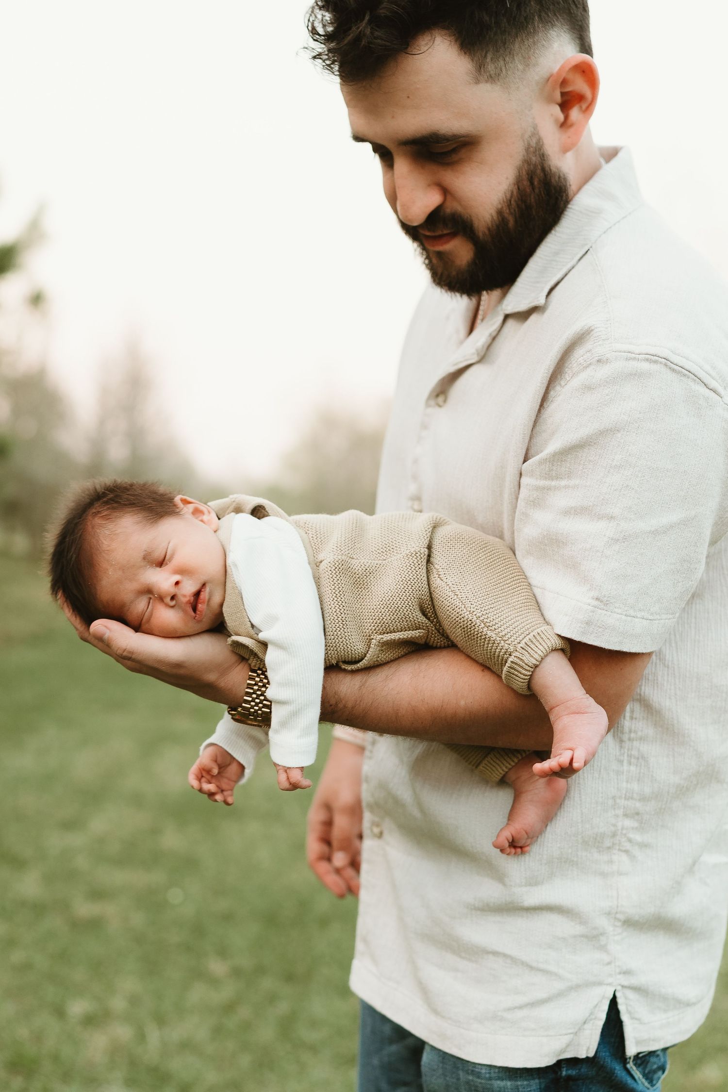 Close-up shots of a newborn baby being held tenderly in light-colored clothing.