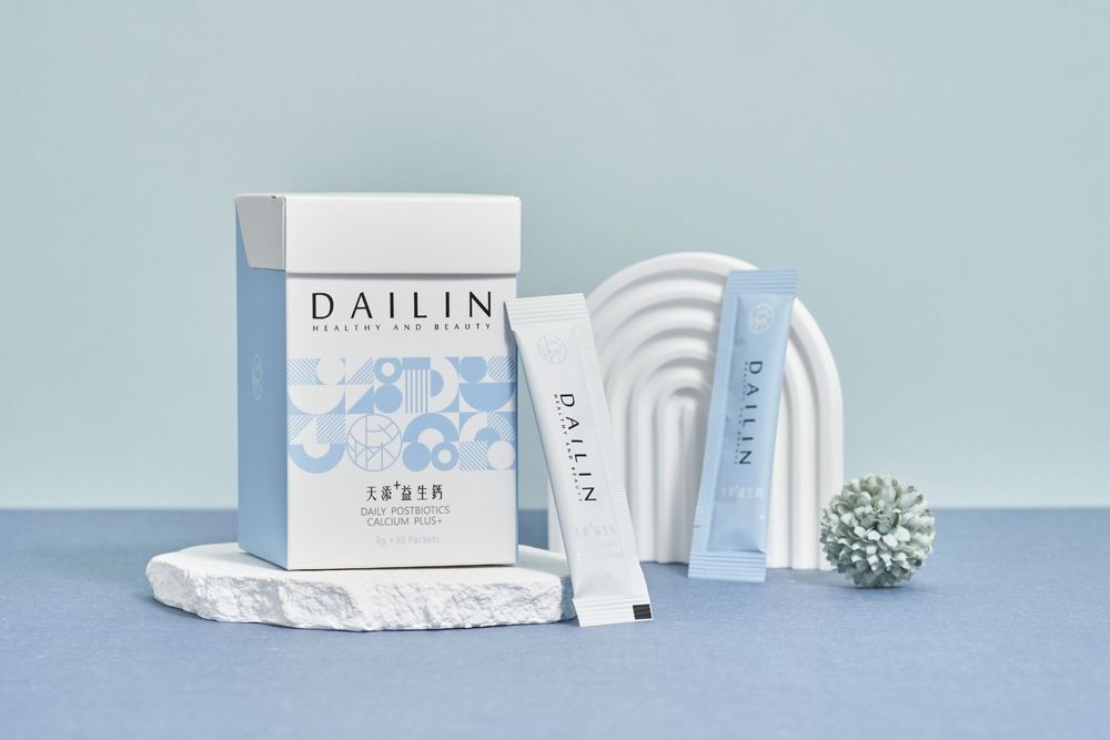 White skincare product packaging and tubes from Dailin brand arranged on a blue surface with decorative elements.