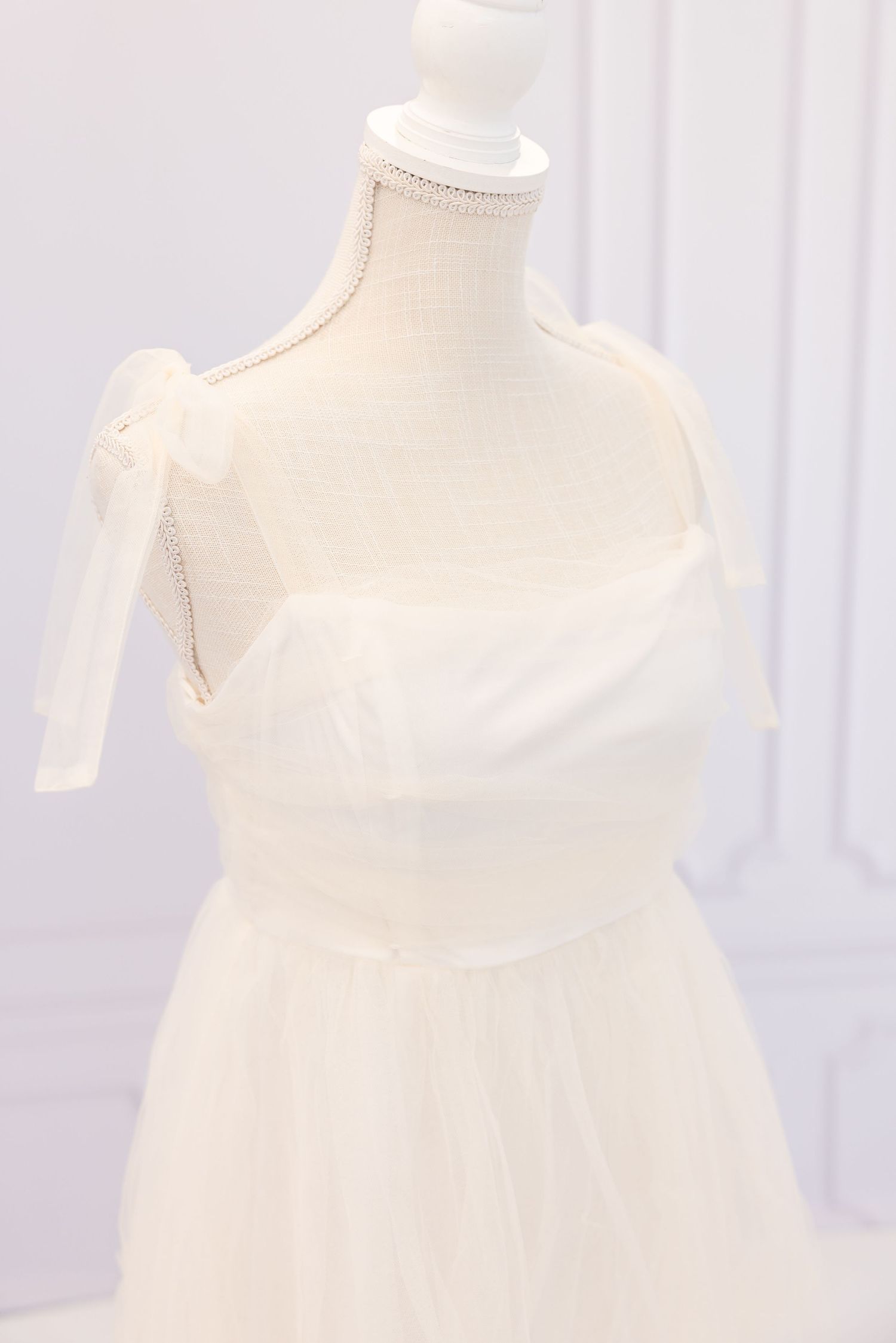 White sleeveless wedding dress displayed on a mannequin form against a light background.