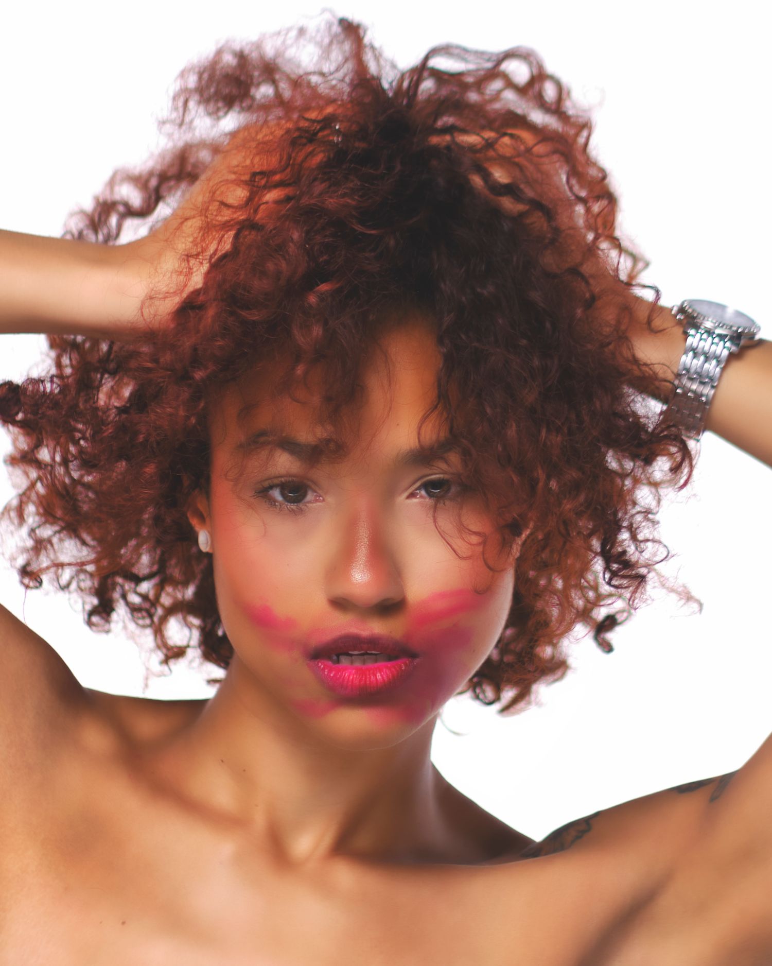 Beauty portrait featuring natural curly hair and bright red lipstick against white background.
