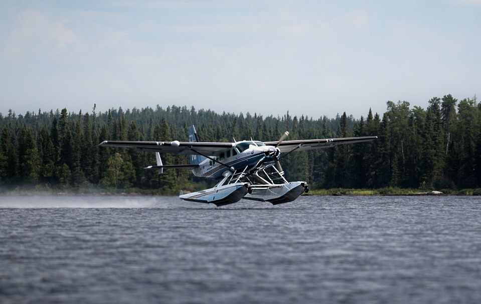 Seaplane landing on remote lake surrounded by dense forest landscape.