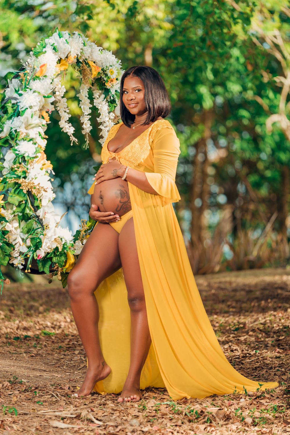 Beautiful maternity photo featuring woman in yellow dress beneath floral archway.