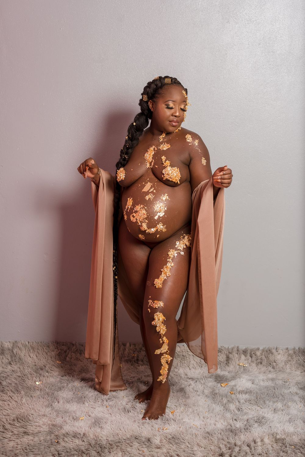 Creative maternity boudoir photo with gold leaf accents on gray backdrop.